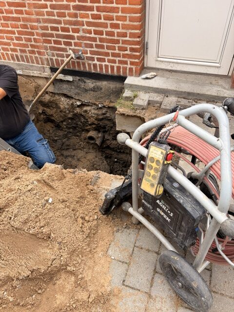 Gravearbejde langs husmuren, hvor kloakledningen er gravet fri
