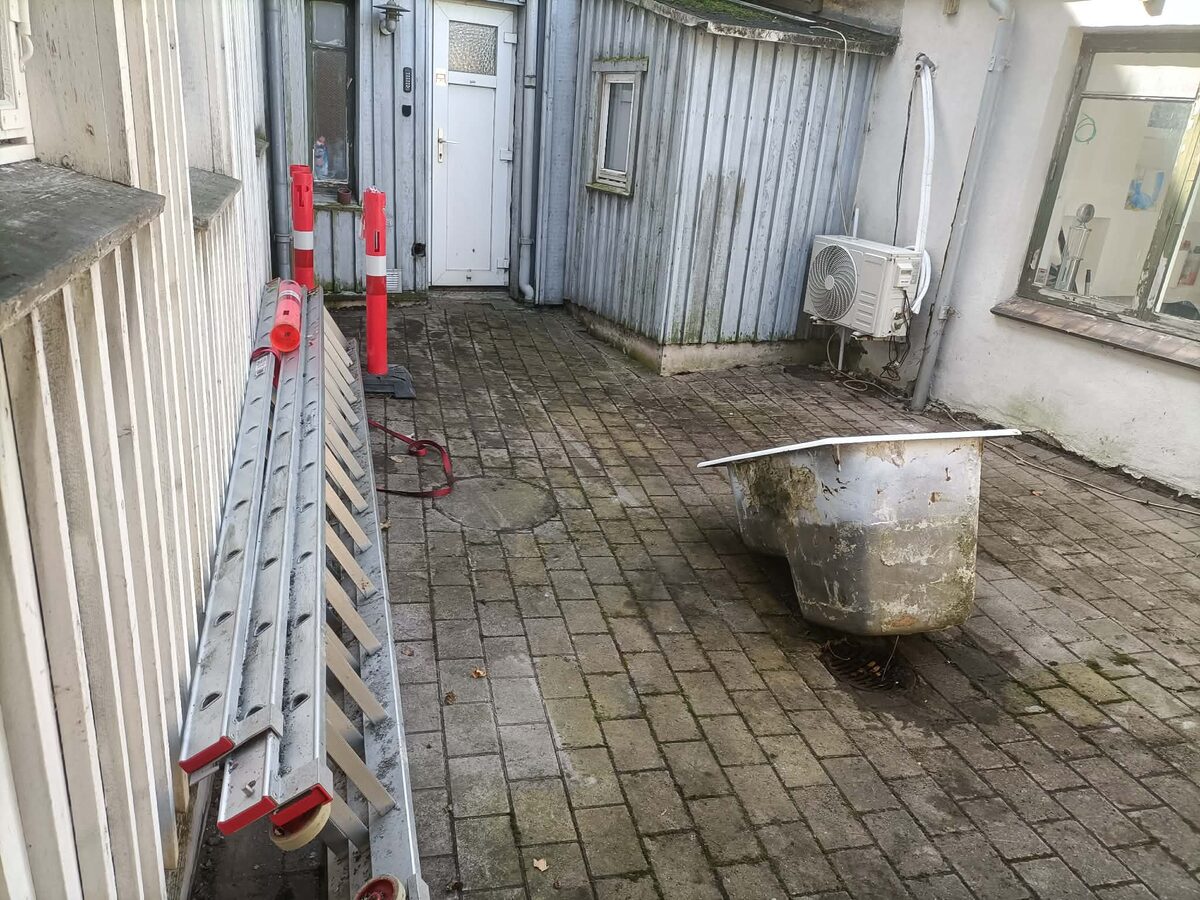 Den ryddede gård med stige og et gammelt badekar