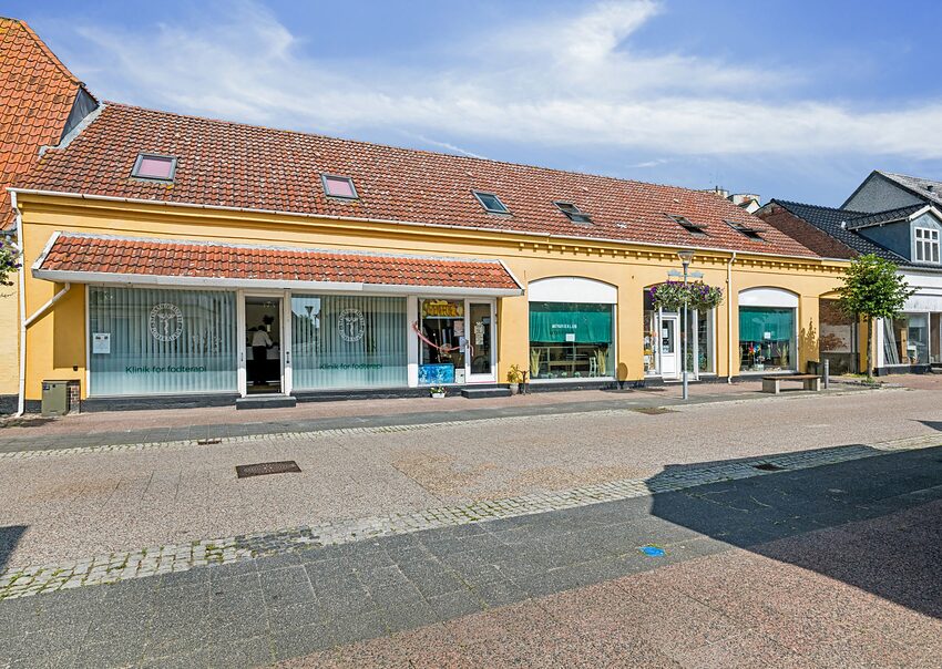 Vestergade 14A-D i Stubbekøbing med gul facade og butiksvinduer ud mod gågaden